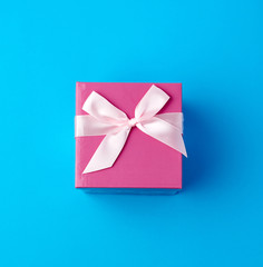 closed pink cardboard box with a bow on a blue background