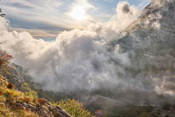 clouds swirl through a mountain valley