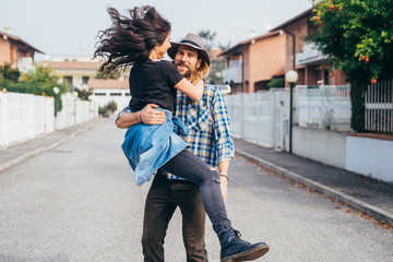 Young beautiful bearded man spinning smiling girlfriend outdoor