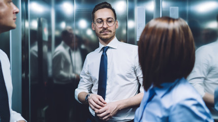 Fototapeta na wymiar Confident colleagues discussing business in elevator