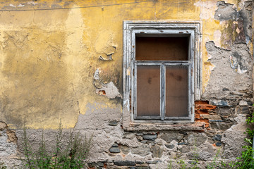 old window on the peeled facade of an old house