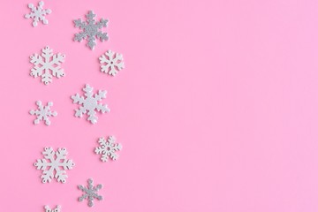 Pink Christmas background with white and silver snowflakes border and empty space for  text, selective focus. New year flat lay with snowflakes decorative border. Winter postcard. 