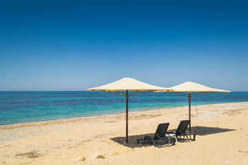 Set of umbrellas and chairs isolated on the beach