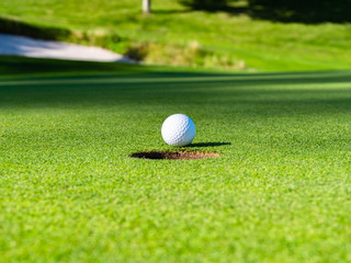 View of golf course putting green with golf ball. Golf course with a rich green turf beautiful scenery.