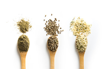 Organic dried hemp seeds, flour, kernels in wooden spoon on white background. View from above.