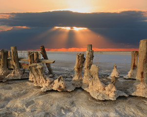 old wooden poles in a salt lake on red sky sunset background