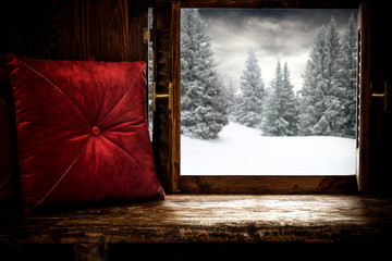 Red pillows on wooden retro window sill and free space for your decoration.Christmas time and landscape of forest with snow and frost decoration.Sunny day and xmas december time. 