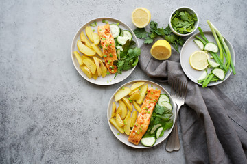 Baked salmon with potatoes and salad. Gray background, flat lay