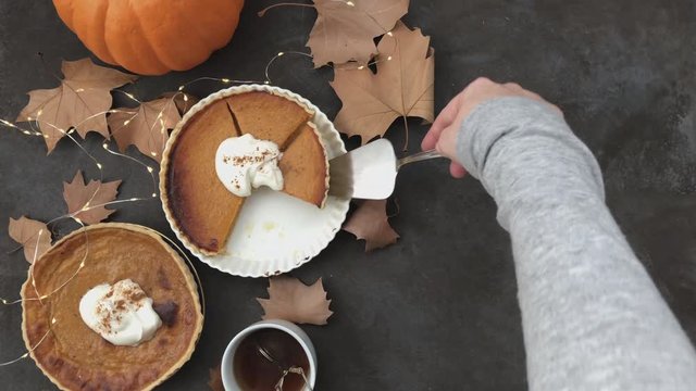 4K Serving pumpkin pie. Flat lay and lights twinkling. 
