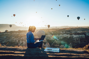 Focused woman using laptop during hot air balloon festival in evening