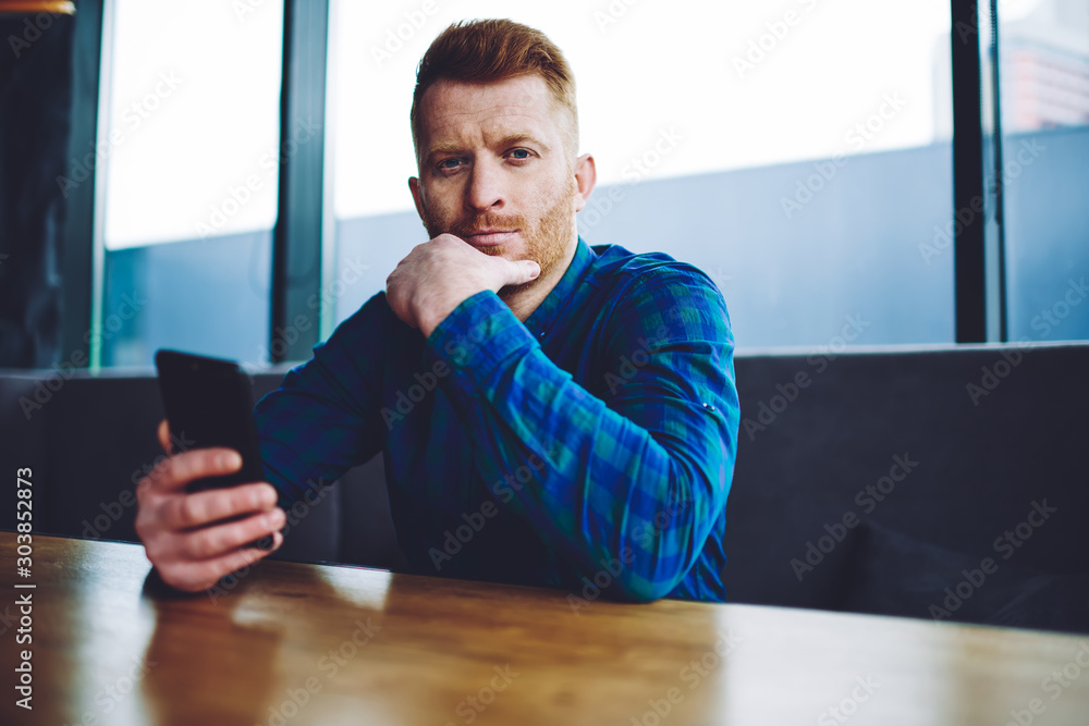 Aufkleber portrait of serious millennial hipster guy spending time with cellphone for updating profile online 