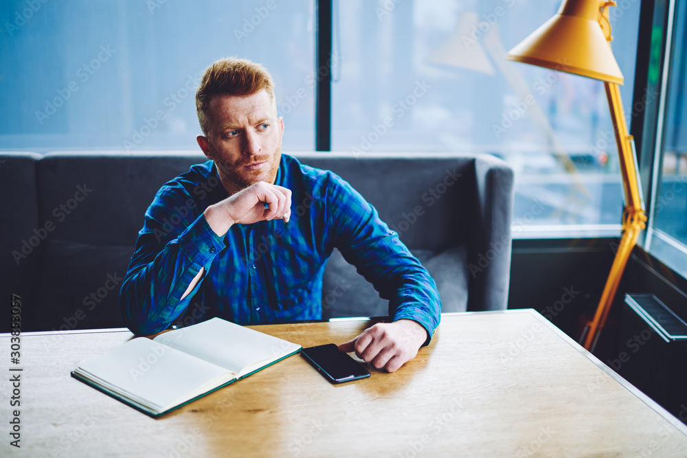Aufkleber pensive hipster guy pondering on idea for content text at own web blog sitting with cellular phone a