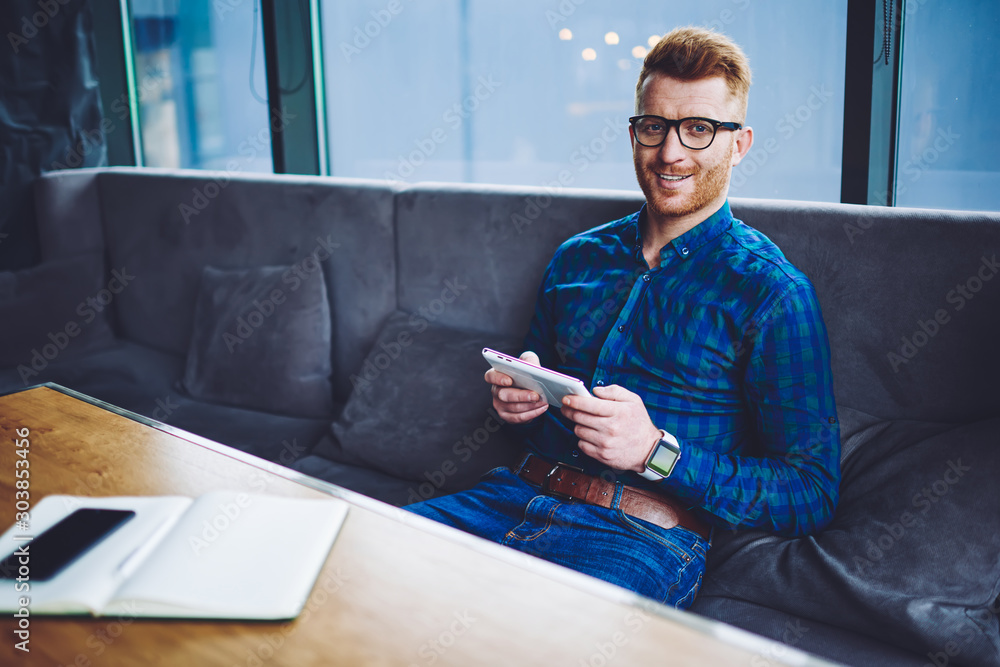 Aufkleber portrait of cheerful man in eyewear looking at camera while resting in cafeteria with digital tablet