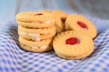 sandwich cookies with strawberry cream placed on a blue and white cloth