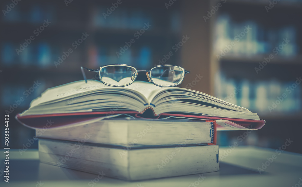 Aufkleber stack of books with glasses placed on the open book in library.