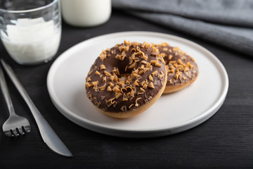 Glazed chocolate donuts on a plate on wooden background