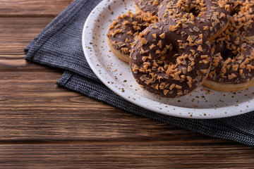 Glazed chocolate donuts on a plate on wooden background