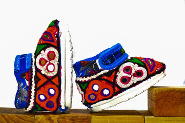 Fototapeta premium handmade baby shoes,Embroidery shoes on wood and white background,gujrati Embroidery,baby shoes on wooden box,