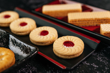 Many cookies are beautifully arranged in a plate and then placed on a wooden table.