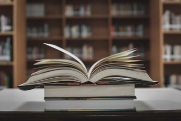 Stack of books in the library and blur bookshelf background