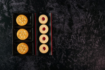 Many cookies are beautifully arranged in a plate and then placed on a wooden table.