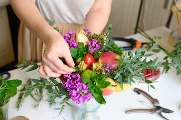 Obraz na płótnie Canvas the process of forming a fruit and flower bouquet. tutorial, do it yourself. photo 27, women's hands inserts a sprig of rosemary into the bouquet