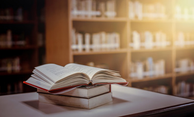 Stack of books in the library and blur bookshelf background