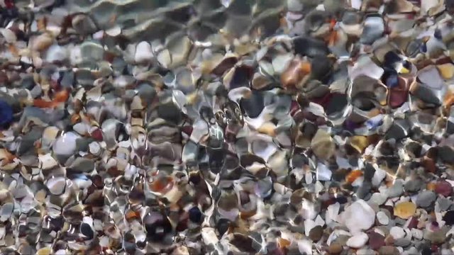 Water running over coloured stones in river