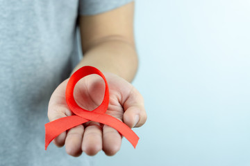 Aids awareness, male hands holding red AIDS awareness ribbon. World Aids Day, Healthcare and medical concept.
