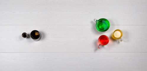 Different colored fruit sodas in different shaped mugs and glasses, top view