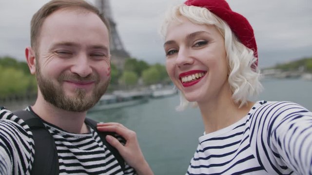 Young tourist couple makes selfie in Paris. Woman kisses a man on cheek.