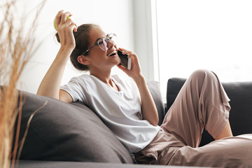 Image of excited nice woman talking on cellphone and holding apple