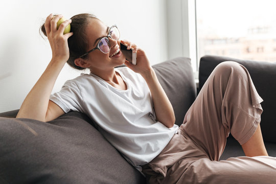 Image of laughing nice woman talking on cellphone and holding apple