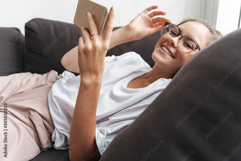 Poster Image of beautiful woman smiling and using cellphone while lying