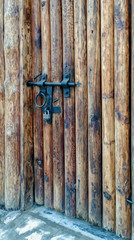Antique wooden doors with a black metal deadbolt and lock.