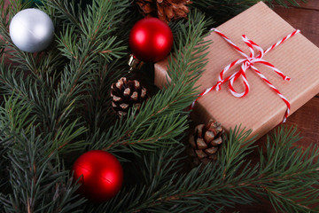 Fototapeta na wymiar Closeup of Christmas gift box, fir tree branch, cones, baubles. Christmas presents. New Year, winter holiday, copy space, top view, celebration