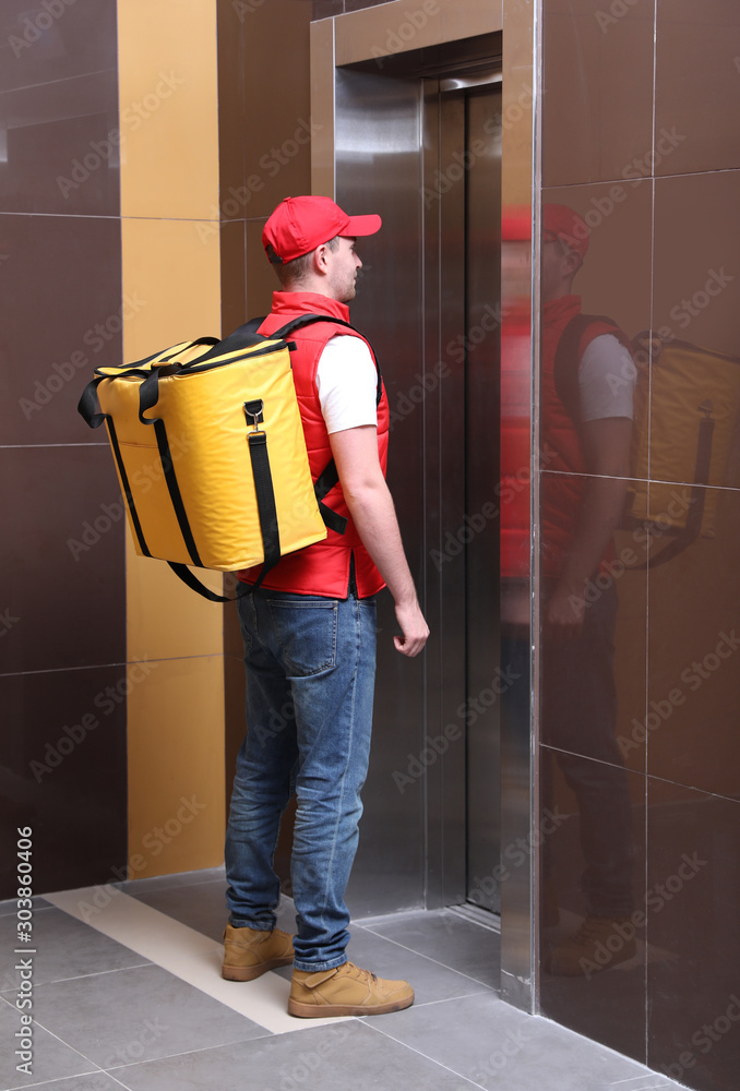 Canvas Prints Male courier with thermo bag waiting for elevator. Food delivery service