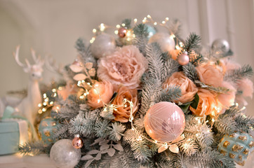 A very beautiful bouquet of fir branches and flowers. Christmas decor with a New Year's garland in gentle pastel shades. Photo in warm tint.