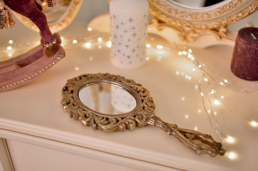 Antique long-handled mirror in gold color. Photo taken in the afternoon in a bright interior.