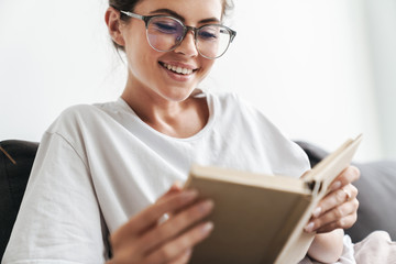 Image closeup of joyful caucasian woman reading book while sitting