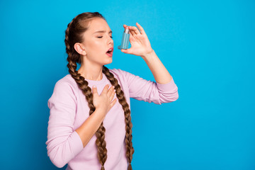 Profile photo of pretty lady with long braids suffering asthma attack using bottle inhaler to stop...
