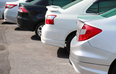 Closeup of rear, back side of soft blue car with  other cars parking in outdoor parking area in bright sunny day. 