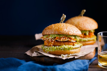 Vegan sweet potato chickpea burgers with avocado guacamole sauce and carrot slaw on dark blue...