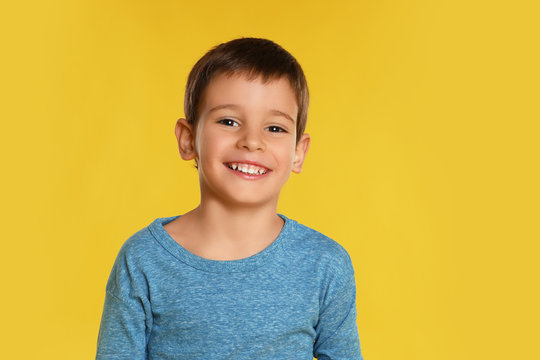 Portrait of happy little boy on yellow background