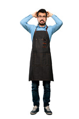 Full-length shot of Man with apron frustrated and takes hands on head over isolated white background