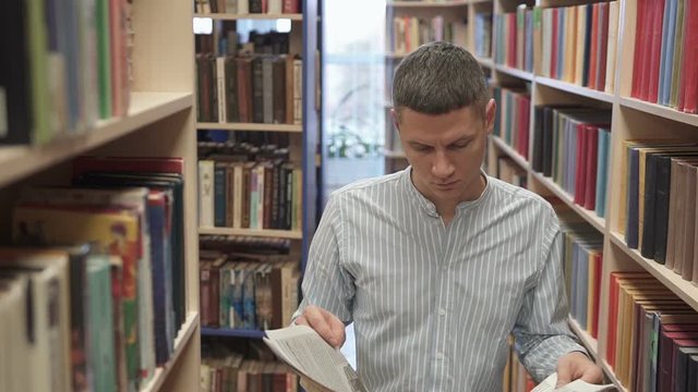 Attractive man reading a newspaper in a library