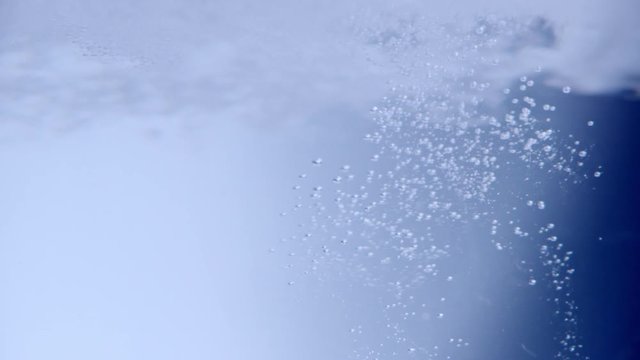 Beady bubbles shot into clear water like an oxygen explosion. Slowmotion 240fps