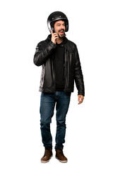 Full-length shot of Biker man keeping a conversation with the mobile phone over isolated white background