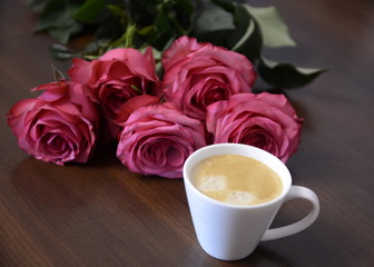 Festive mood. A bouquet of fresh fragrant pink roses for lovers and a white cup of coffee.