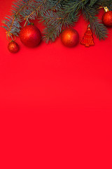 Evergreen branch with red Christmas ball on red background. New Year banner with place for text